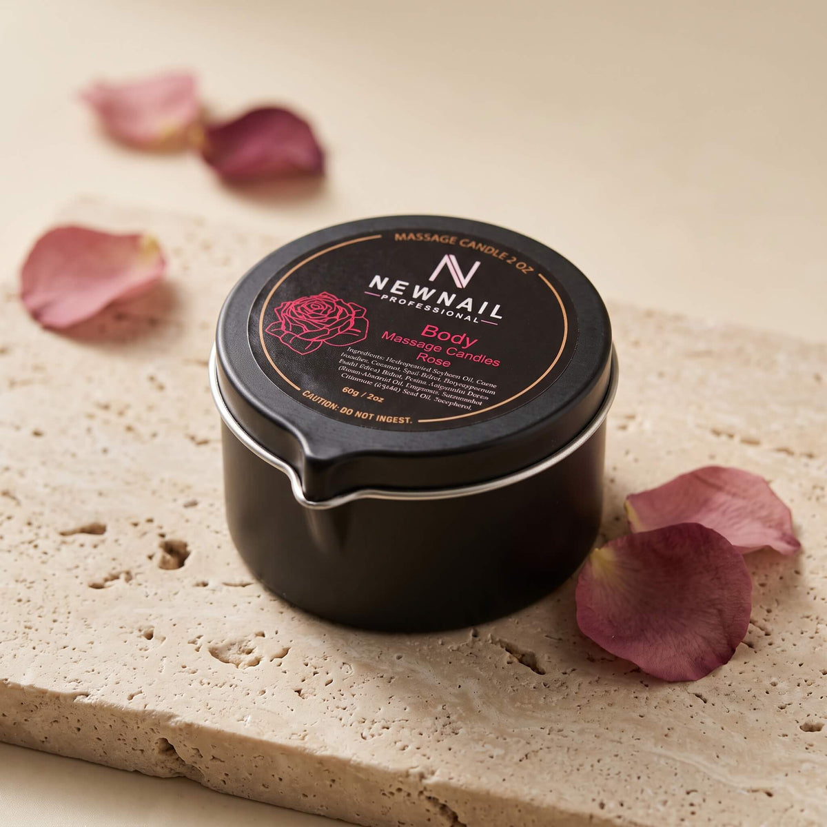 Rose massage candle on a stone surface with rose petals